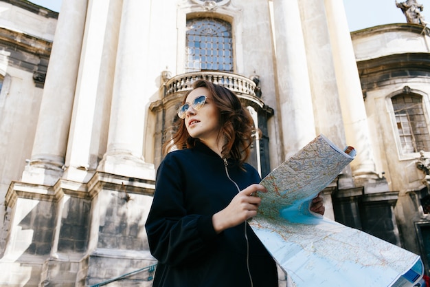Femme tient la carte touristique dans son bras, debout devant la vieille cathédrale
