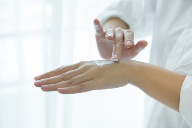 femme tient un pot avec une crème cosmétique dans ses mains