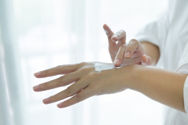 femme tient un pot avec une crème cosmétique dans ses mains