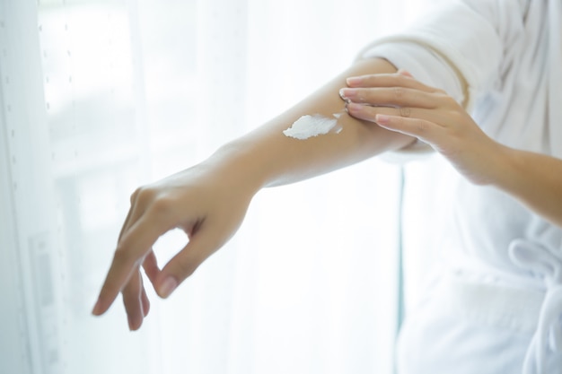 femme tient un pot avec une crème cosmétique dans ses mains