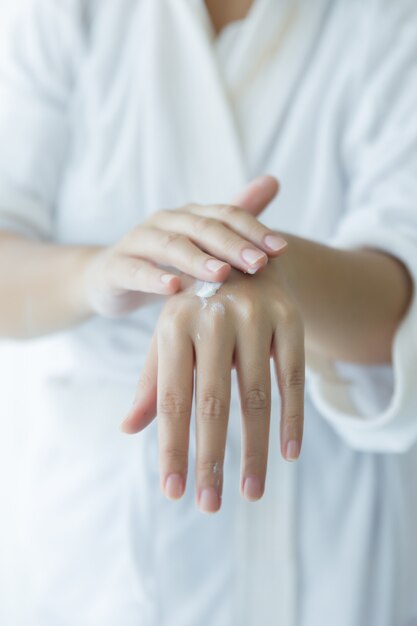 femme tient un pot avec une crème cosmétique dans ses mains