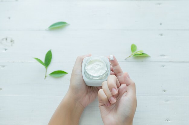 femme tient un pot avec une crème cosmétique dans ses mains