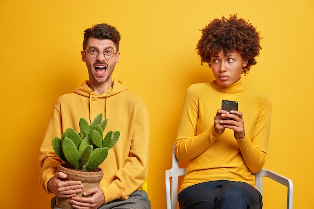 Une Femme Tient Un Smartphone Moderne Et Un Homme Crie En Tenant Une Plante