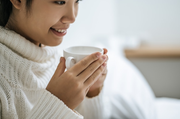 Une femme tient une tasse de café.