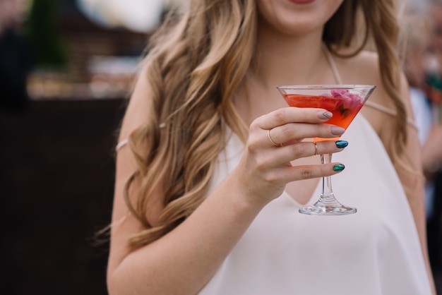 Femme tient verre de cocktail dans sa main