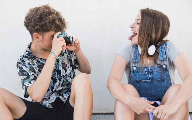 Femme tirant la langue alors que son copain prend une photo avec un appareil photo