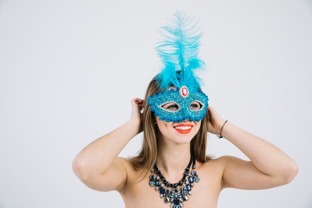 Femme topless souriante portant un collier et un masque de carnaval mascarade