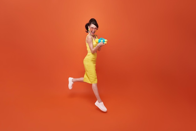 Femme de tourisme sautant voyageant avec un pistolet à eau pendant le festival de Songkran