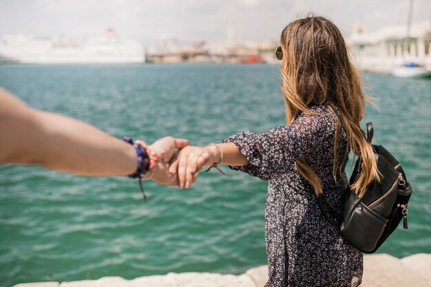 Femme touriste regardant la mer tenant la main de son petit ami