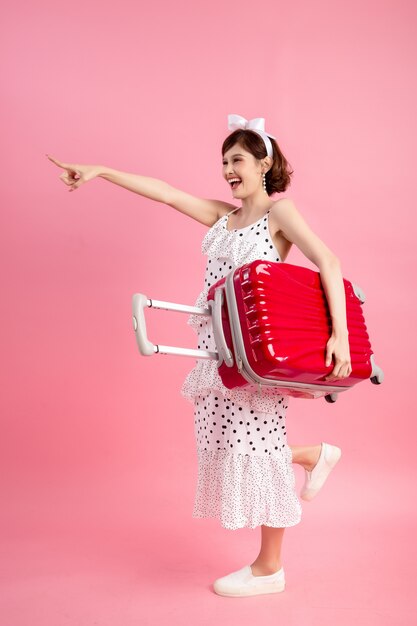 Femme touriste voyageur en vêtements décontractés avec valise de voyage isolé sur rose