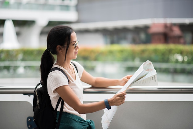 Femme touristique avec la carte de la ville à la recherche de destination