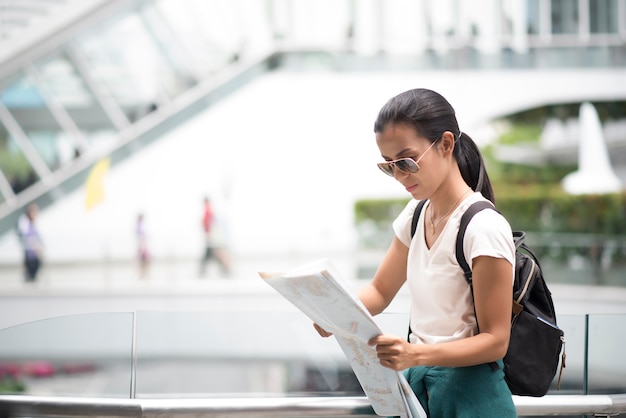 Femme touristique avec la carte de la ville à la recherche de destination