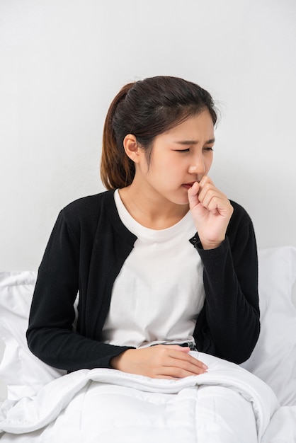 La Femme Toussa Et Couvrit Sa Bouche Avec Sa Main Et S'assit Sur Le Lit.