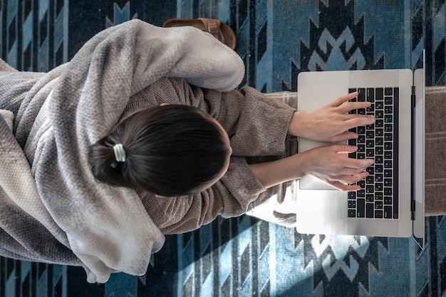 Une femme travaillant assis devant un ordinateur portable vue de dessus