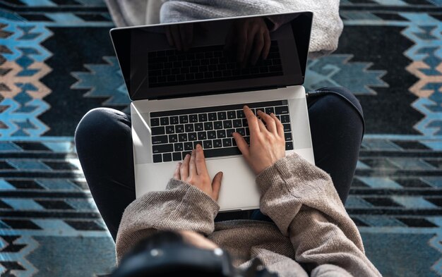 Une femme travaillant assis devant un ordinateur portable vue de dessus