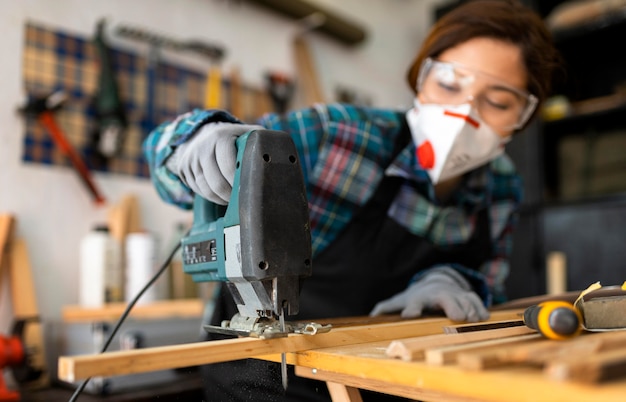 Femme travaillant en atelier avec perceuse à percussion