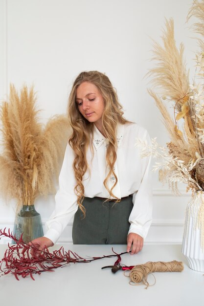 Photo gratuite femme travaillant avec des fleurs séchées coup moyen