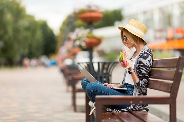 Femme travaillant et mangeant sur un banc