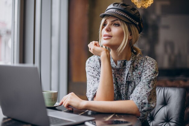 Femme travaillant sur ordinateur et buvant du café