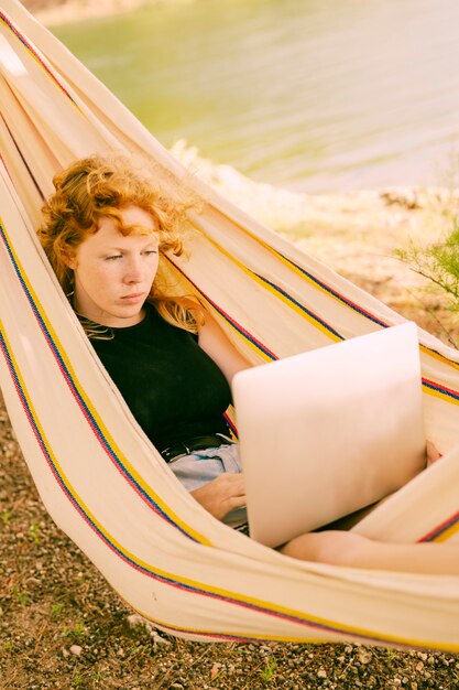 Femme travaillant sur un ordinateur portable dans un hamac