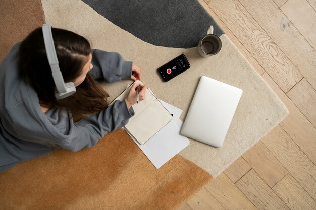 Femme travaillant sur le sol depuis la maison avec un appareil