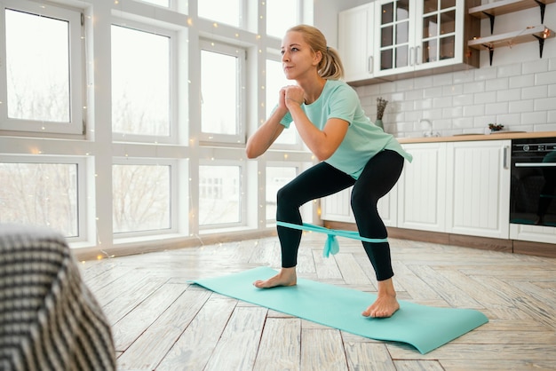 Photo gratuite femme travaillant sur tapis avec bande élastique