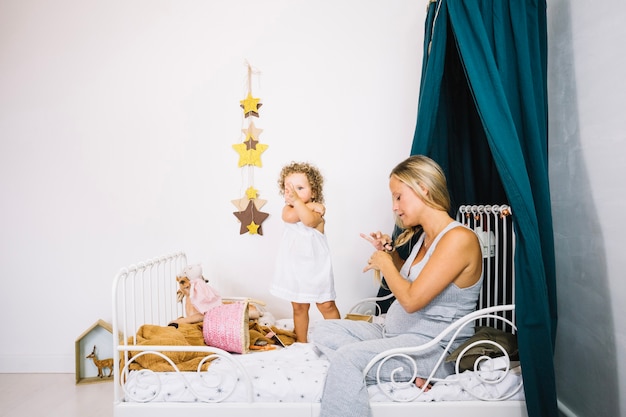 Femme tressant les cheveux près de bébé mignon