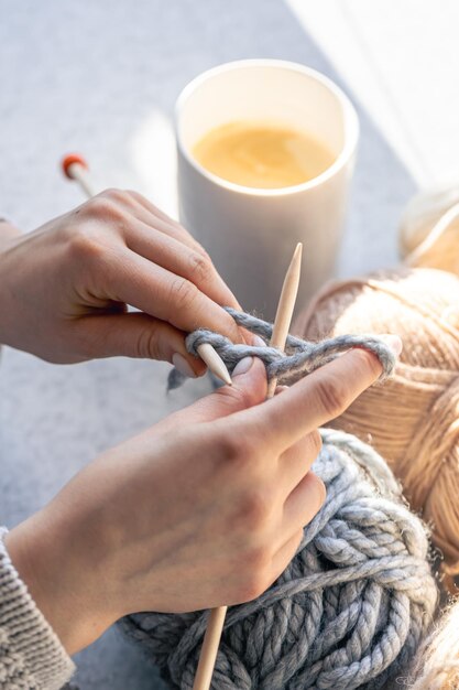 Une femme tricotant avec un fil gris en gros plan