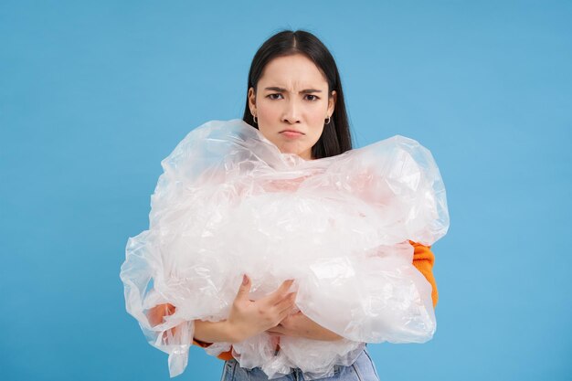 Photo gratuite femme triste asiatique tenant des ordures en plastique et fronçant les sourcils de déception combattant la pollution ecoactivi