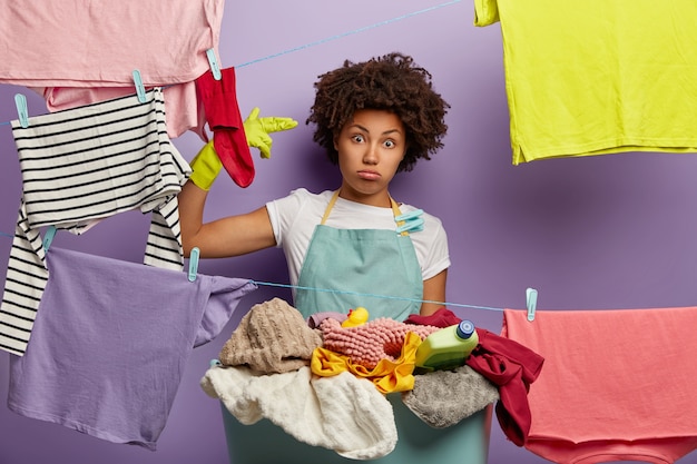 Une Femme Triste Et Déprimée Fait Un Geste De Suicide, A Beaucoup De Travail à La Maison, Habillée D'un Tablier Décontracté, Se Lave Pendant Le Week-end, Accroche Des Vêtements Propres, Pose à L'intérieur.