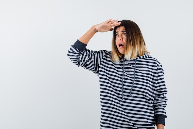 La femme triste essaie de regarder loin en tenant sa main sur le front sur fond blanc