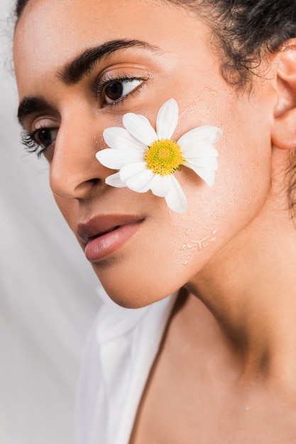 Photo gratuite femme triste ethnique avec fleur sur le visage