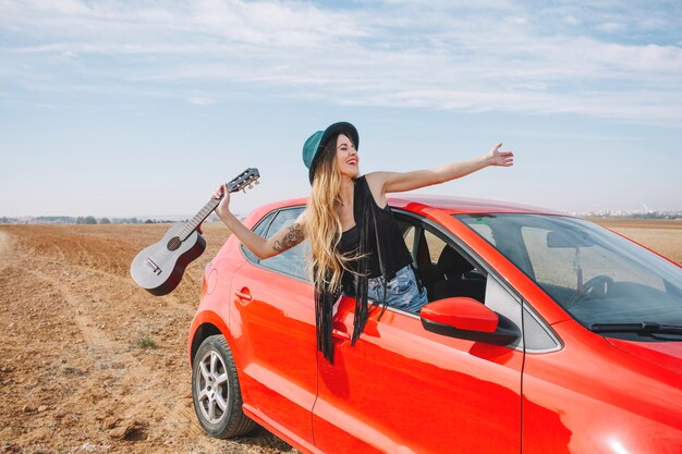 Femme avec ukulélé dans la fenêtre de la voiture