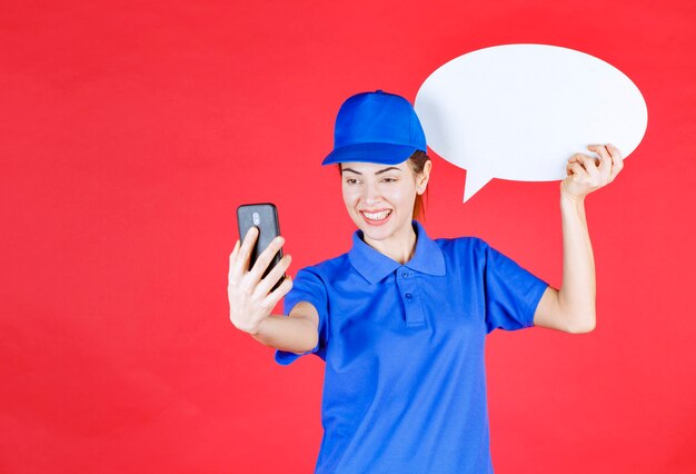 Femme en uniforme bleu tenant un tableau d'idées ovale et passant un appel vidéo.