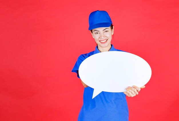 Femme en uniforme bleu tenant un tableau d'idées ovale.