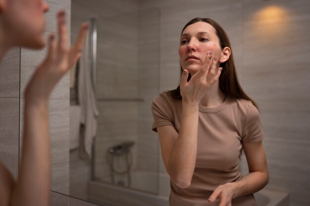 Femme utilisant une crème hydratante pour aider avec l'état de la peau de la rosacée