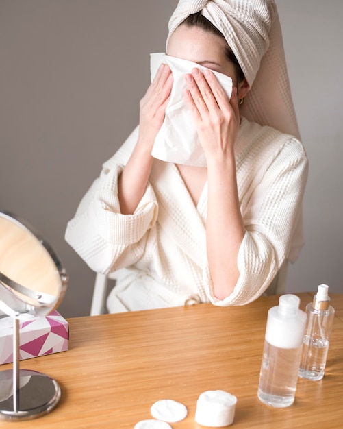 Femme utilisant de l'eau micellaire pour enlever le maquillage