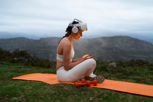 Photo gratuite femme utilisant des lunettes vr pour faire de l'exercice à l'extérieur dans la nature