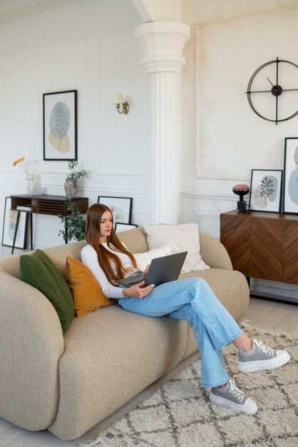 Photo gratuite femme utilisant un ordinateur portable dans une chambre décorée avec un minimum