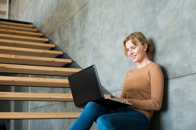 Femme utilisant un ordinateur portable dans les escaliers