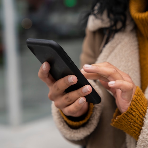 Photo gratuite femme utilisant son smartphone à l'extérieur