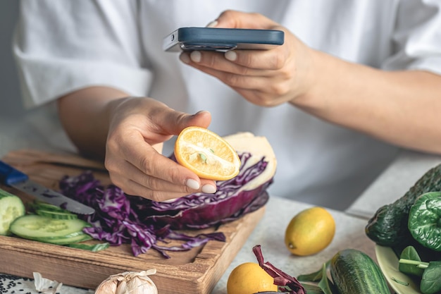 Photo gratuite une femme utilise un smartphone et tient un limequat dans sa main