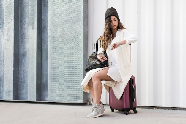 Photo gratuite femme sur la valise en regardant la montre