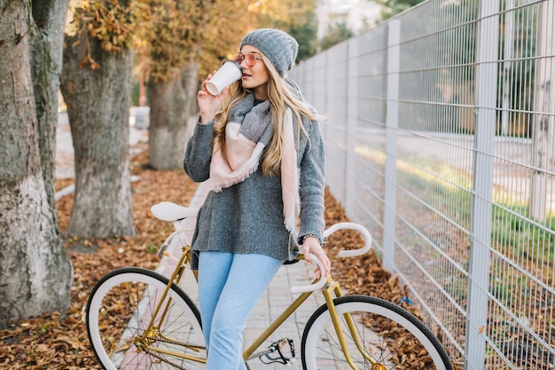 Photo gratuite femme avec vélo et boisson chaude