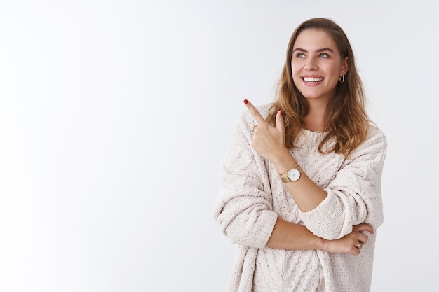 Femme vérifiant l'exposition d'un ami exprimant son opinion pointant du doigt l'air amusé ravi souriant largement discutant du produit, debout satisfait pose détendue, fond blanc insouciant