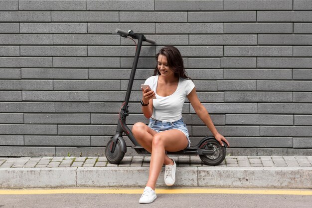 Femme vérifiant son téléphone alors qu'il était assis sur un scooter