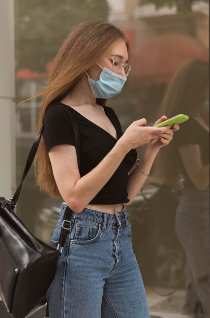 Femme vérifiant son téléphone tout en portant un masque médical
