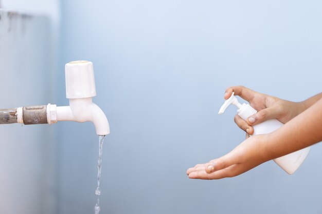 Femme versant du savon dans sa main à partir d'une bouteille de presse à main