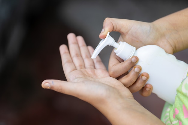 Femme versant du savon dans sa main à partir d'une bouteille de presse à main