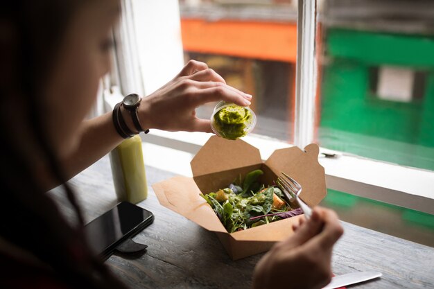 Femme versant la sauce verte sur une salade